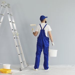 Bearded painter painting the wall with paint roller.