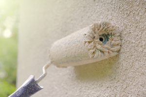 A close view of roller painting the walls of the house in beige color