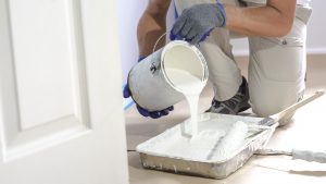 Close up of painter hands with gloves painting the wall edge with brush. 