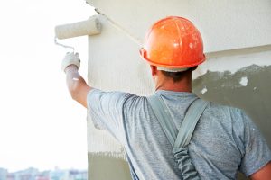 A builder worker with roller at thermal insulation works