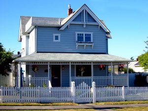 A blue house with white trim and a white picket fence.